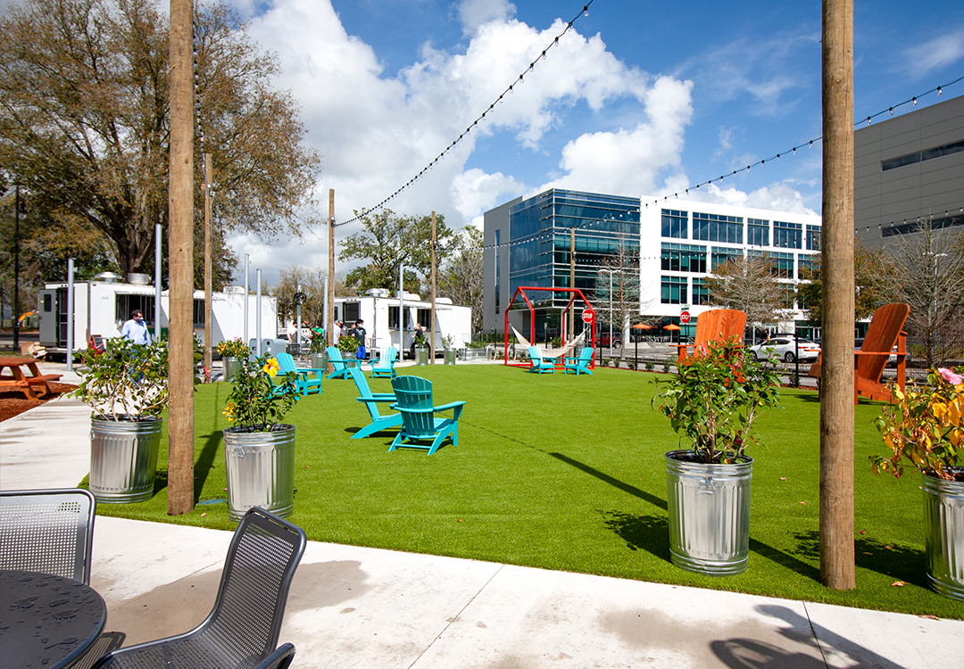 image of the grassy lawn, tables, chairs, and restaurants at midpoint park and eatery